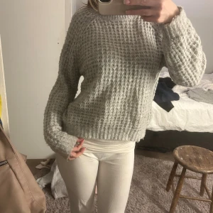 Ljusgrå stickad tröja med struktur - Säljer en ljusgrå stickad tröja med grov, strukturerad yta och ribbade muddar vid ärmslut och nederkant. Tröjan har en rund hals och långärmade, lite loose passform som ger en chill vibe. Perfekt för att hålla sig varm och snygg under kyliga dagar.