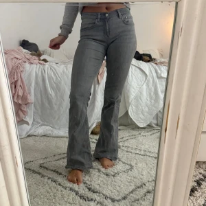 Grå bootcut jeans från Perfect Jeans - Snygga grå jeans från Perfect Jeans i bootcut-modell med hög midja. Jeansen har klassisk femficksdesign och är tillverkade i stretchigt denimtyg som sitter riktigt bra. Perfekta för dig som gillar en stilren och trendig look.