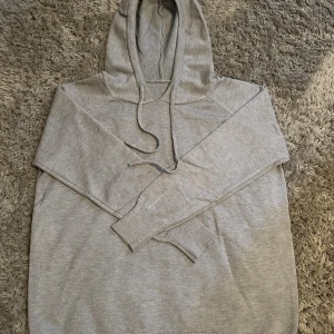 Grå kashmire hoodie  - En stilren grå hoodie med huva och snörning framtill. Tröjan har långa ärmar med ribbade muddar och en mjuk känsla. Perfekt för chill dagar och enkel att matcha med jeans eller joggers. Klassisk passform och neutral färg som funkar året runt.
