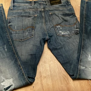 Jack & Jones Slim Glenn jeans 28/32 - Snygga blå jeans från Jack & Jones i modellen Slim Glenn. Jeansen har slitna detaljer. Kan göra byten och sänka priset vid snabb affär