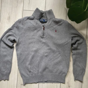 Ralph Lauren half zip - Snygg grå stickad tröja från Polo Ralph Lauren med half zip och hög krage. Tröjan har långärmad passform, ribbade muddar och en broderad röd logga på bröstet. Perfekt för dig som gillar klassisk stil med en modern touch. storlek XS men passar S lika bra