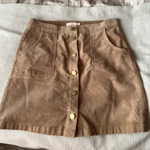 Tori Burch  - Manchester kjol med tryck knappar. Köpt i New York.   Snygg till en stickad gosig tröja och strumpbyxor nu på hösten eller bara ben och ett linne till sommaren.   Köparen betalar fraktkostnad på 49kr spårbar frakt  Stl S