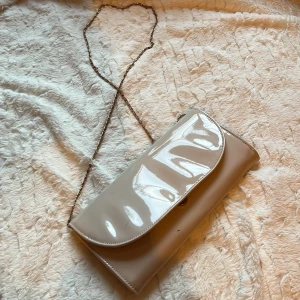 fin glansig kuvertväska  - hej! säljer denna jättefina beiga glansiga kuvertväskan, som tyvärr har några repor på sig men annars är den så himla fin! 