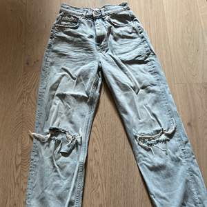 Ljusblå högmidjade vida jeans med hål på knäna från gina tricot, säljer pågrund av att jag inte fått användning för de tyvärr, köparen står för frakten storlek xs