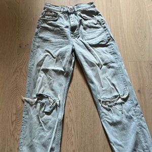 Högmidjade ljusblå jeans från Gina Tricot aldrig använda storlek xs - Ljusblå högmidjade vida jeans med hål på knäna från gina tricot, säljer pågrund av att jag inte fått användning för de tyvärr, köparen står för frakten storlek xs
