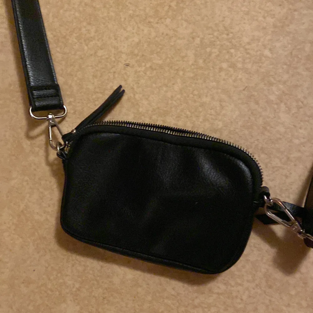 En svart handväska som är rätt så använd. Men ser ut som ny stick. Super bra väska om man ska åka och shoppa och kunna ha sin mobil där i.. Väskor.