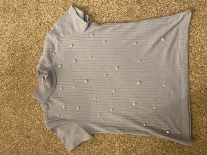 Blå t-shorts med pärlor - Jag säljer denna blåa t-shirten för att den är för liten. Jag har använt den ganska men den är såklart tvättad när den fraktas. Jag säljer den för 30kr. Den är i storlek 128❤️förlåt för att bilden blev upp och ner, det blev nåt fel