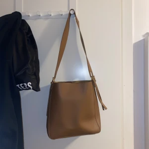 Stor axelväska - Ljusbrun/mörk beige axelväska med utrymme för dator, bäcker eller andra störta saker. Använd få gånger. 26x27 cm. Lägsta bud: 65