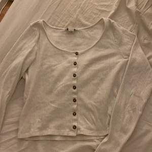Ribbad topp med knappar - Krämvit ribbad topp med knappar framtill. Från Monki. Storlek S. Säljer pga flytt.
