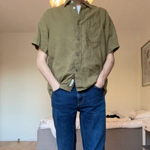 Linneskjorta från Arket - Mörkgrön linneskjorta från Arket i storlek 48. Den är stor på mig som oftast har storlek 46/48. Färgen ser olika ut beroende på ljus, men i vanligt dagsljus är den mörkgrön.