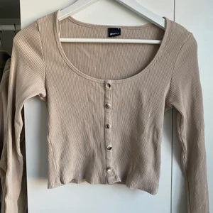 CROP TOP RIBBAD - Ribbad croptop med ”fake knappar”, långärmad, rundad hals