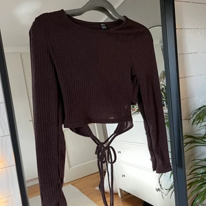 Brun ribbad med knyt i ryggen - Brun ribbad tröja med knytning i ryggen och väldigt stretchig, aldrig använd
