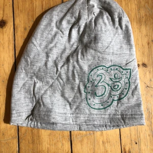 Mössa/beanie fleecefodrad - egen design🕉 - Unik och skön mössa i egen design 🕉 fleecefodrad så perfekt för vinter eller kalla vår/sommarkvällar. Rymlig modell, se bild 2 för jämförelse i storlek. Ekologisk bomull och screentryckt. Endast ett exemplar!