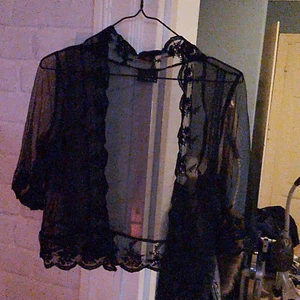 Spets bolero  - Genomskinlig aftonbolero med spetsvirkade blommönster runt. Halvlängd på armar 