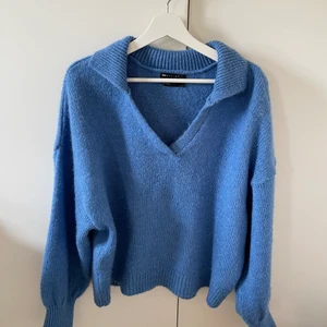 Blå stickad tröja  - Blå stickad tröja med balongärmar och krage.