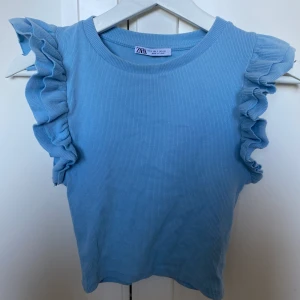 Blå topp med volanger - Populär blå volangtopp från Zara som funnits i många färger. Använd ett fåtal gånger. Köparen står för valfri frakt