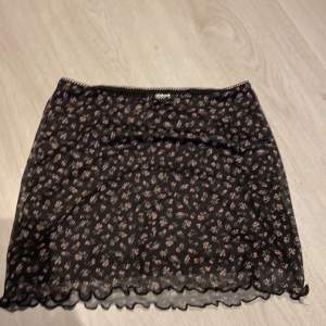 En svart blommig mini skirt i storlek xxs oanvänd (köparen står för frakt)