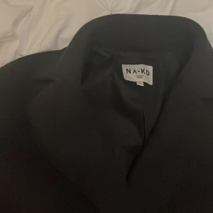 Mörkgrå NA-KD kappa - Mörkgrå/svart NAKD kappa i stl 32. Använd en gång. Väldigt fint skick. Lite stor i storleken.