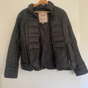 Dunjacka - Säljer en tunn dunjacka som inte kommer till användning. Perfekt att ha under tunnare kappor! använd en vinter, har ett hål under höger arm vid armhålan ungefär. Lätt igensytt!