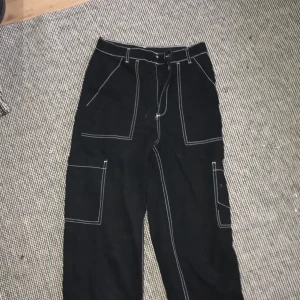 Svarta byxor med vita sömmar - Fina byxor inköpt för ungefär ett år sedan från H&M. I bra skick då de knappt är använda. Byxorna är väldigt figurnära och sitter bra.