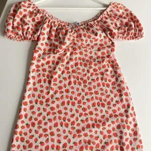 Jordgubbsklänning  - Kort sommarklänning med rosa/rött jordgubbsmönster perfekt till sommaren, jordgubbens dag eller midsommar. Storlek S. Kortärmad som går att både ha på axlarna och som off shoulder🫶🍓🥰kom gärna med prisförslag eller köp dirket☺️