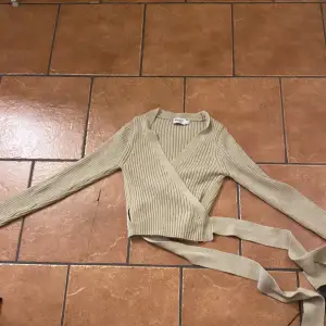 Stickad omlott tröja med knytning 