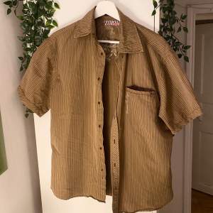 beige/brun/orange randig skjorta i typ storlek L köpt second hand.  bra skick, skriv om du har några frågor :)