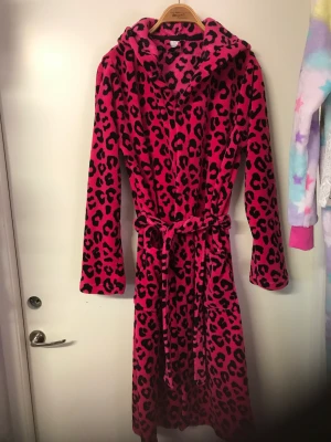 Mjuk färgglad morgonrock  - Super mjuk skön rock med huva från bodyzone by Kappahl. Ceris rosa och svartmönstrad. Storlek 170