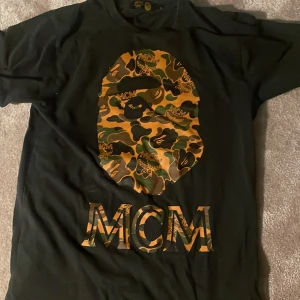 Bape x MCM t-shirt storlek Small - Köpt från BAPE MCM pop up butik i Berlin, använd ett par gånger. BAPE printet på framsidan av tröjan i bra skick.