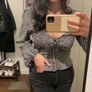 Mönstrad blus - Säljer denna ursöta mönstrade blus (blommönster) som tyvärr inte kommit till någon användning. Svartvit färg med någon färgdetalj i självaste blomman.  Nyskick med prislapp kvar.  Storlek S.  Möts upp eller fraktar 💘