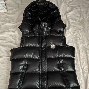Moncler väst med huva - Säljer denna moncler väst med huva för att den känns lite för liten då jag växt, tänker att ingen kommer köpa den för det pris den igentligen säljs för så jag sänker den från 6700 till 1800, den är äkta och alla koder och NFC chip funkar!