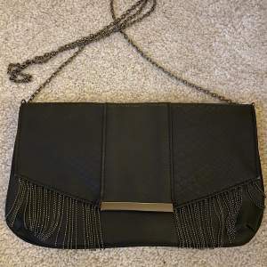 En svart väska med silver ”strings” som hänger ner, 90-talet. anledning: används inte så mycket längre. 💕använd 3-8 ggr. Pris inkl frakt. Läder. Rött inuti väskan!💙