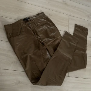 Bruna byxor i imitationsläder - Extremt snygga byxor i läder-aktigt tyg. Brun färg och glansig till yta. 