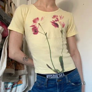 Gul graphic tee t-shirt blommor 90s stort tryck - Ljusgul graphic tee med ett stort tryck av två mörkrosa blommor 🌺🌺 Älskar färgerna och att trycket är över hela framsidan! 