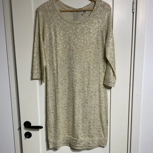 Guldklänning  - Guldglittrande klänning i rak modell. Liten dragkedja bak.  Från Vero Moda  Stl S Fint skick!