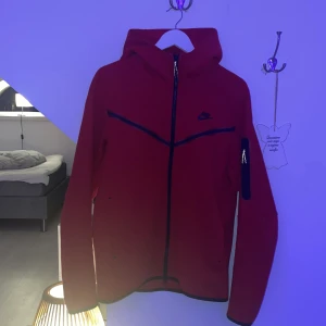 M - Nike Tech Hoodie - En röd nike tech hoodie i storlek M. Använder inte den så den tar endast upp plats i garderoben. 10/10 skick. Har använts max 5 gånger.