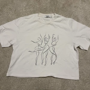 Vit croppad T-shirt  - En vit T-shirt från NA-KD med detta snygga tryck! Lite boxig/oversized modell och lite croppad. I strl xs men passar större också 😊 knappt använd så trycket är i mycket bra skick 💖