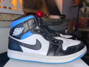 Air Jordan 1 Mid White/Black-University-Blue - Air Jordan 1 Mid   White/Black-University-Blue • Storlek 40,5 men passar lätt 41  (Mina andra par J's är 41). • 9,5/10 i toppskick med lite Crease och Smutsiga Undersulor. • Modellen är WMNS (men jag själv är snubbe med breda fötter)