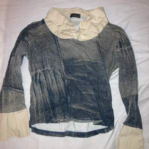 Unik och snygg tröja med inbyggd krage. Tyget är bomull med tryck på så att det ser ut som jeans, vilket är en cool och unik detalj. Färgen är beige och gråblå.