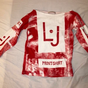 Röd och vit snygg topp - Snygg långärmad tajt tröja, är lite åt magtröja-hållet.  Coolt tryck. Snygg att ha som den är eller med accessoarer. Väldigt skön dessutom!!