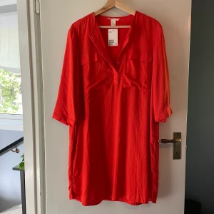 Skjortklänning röd H&M - Skjortklänning från H&M. Aldrig använd, prislappen sitter kvar. Går strax under knäna på mig, jag är 160cm. 