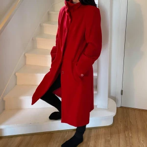 Röd ull kappa från HM stl 36 - Snygg röd ull kappa från HM. Köpt tidigt 2000tal. Nyligen kemtvättad. Bra skick trots att den är använd väl. 