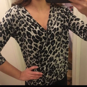 Leo topp Lindex - En leo topp i ljusgrått, mörkgrått och svart från Lindex i storlek S i bra skick. Armarna går nedanför armbågarna. Toppen är en omlott-modell