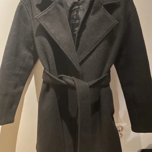 Kort Kappa NA-KD  - Kort Kappa från NA-KD  Storlek 34  Färgen är mörk grå  Skickar spårbart för allas trygghet😊 Köp plagget genom att trycka på ”köpknappen” men har du frågor går det bra att kontakta mig här💞