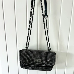 Glittrig väska - En liten glittrig väska. Två fack ett större ett mindre. Säljer då den inte kommit till användning mer än en gång.  