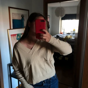 Finstickad tröja - Beige finstickad tröja, den har två fickor på sidan och är v-ringad