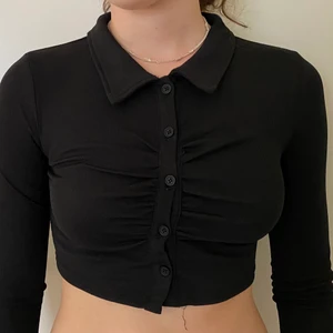 Svart topp från SHEIN - strl 34/Xs  - En jätte fin crop top från SHEIN. Aldrig använd. Den är lite ribbad med knappar framtill, lite veck & en krage 🖤