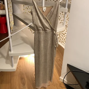 Guldig klänning - Guldig klänning som går en bit nedanför knäna. Passar S-M