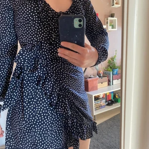 Mörkblå sommarklänning  - Mörkblå omlott kläning från NA-KD med volanger och små vita prickar. Klänningen är i storlek S men passar den som brukar ha  36-38 i storlek. Som ny, använd max 2gånger, jag säljer den då jag inte har fått användning av den💗 fraktkostnad står köparen för om inte möte funkar! 