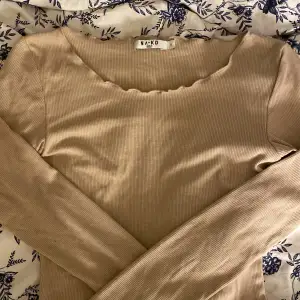 En tunn ribb stickad tröja från NA-KD, helt oanvänd. Super mjuk i material och har volang detaljer vid slutet av armarna och längst ner på tröjan. Jättefin beige färg 